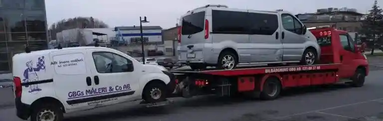 Äldre bil med motorhuven öppen vid en verkstad där mekaniker undersöker kostsamma reparationer.